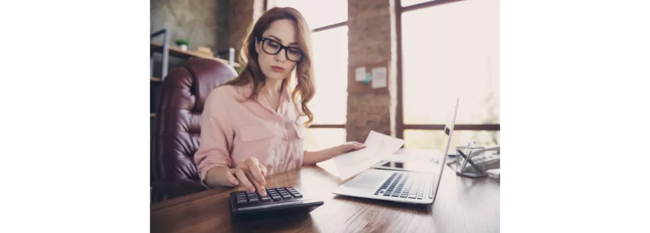 Ce inseamna indexarea salariilor pentru o companie vs. pentru angajati - femeie la birou, laptop, calculator- Pluxee Romania 