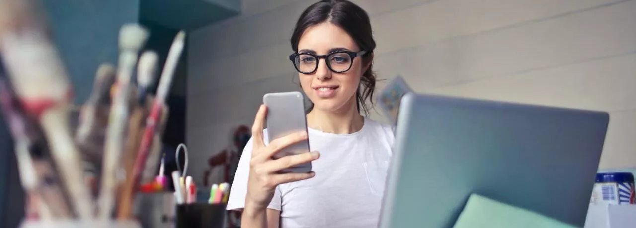 Generația Z motivare - femeie, telefon, laptop, birou - pluxee.ro